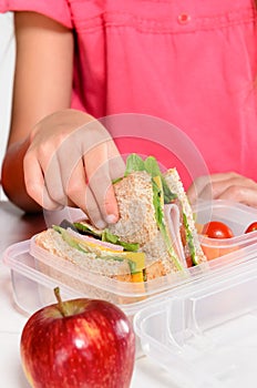 Child removing wholemeal sandwich out of lunchbox