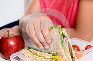 Child removing wholemeal sandwich out of lunchbox