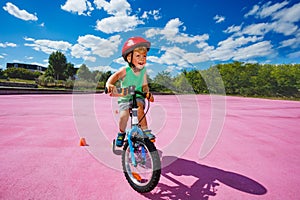 Child ride small bicycle with learning wheels around cones