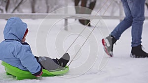 A child rides a sled in winter and smiles for the camera