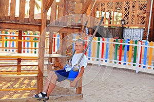 The child rides on a swing in the playground.