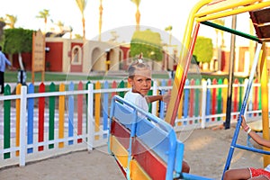 The child rides on a swing in the playground.