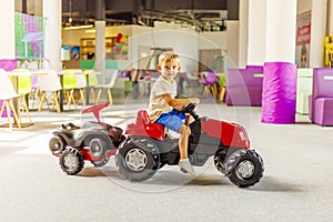 A child rides a toy pedal car at a children's play center