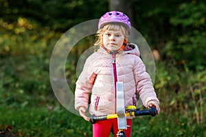 Child riding balance bike. Kids on bicycle in sunny forest. Little girl enjoying to ride glider bike on warm day