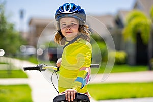 Child riding bicycle. Little kid boy in helmet on bicycle along bikeway. Happy cute little boy riding bicycle in summer