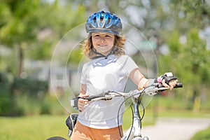 Child riding a bike in summer park. Children learning to drive a bicycle on a driveway outside. Kid riding bikes in the