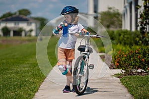 Child riding a bike in summer park. Children learning to drive a bicycle on a driveway outside. Kid riding bikes in the