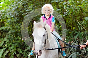 Child riding horse. Kids ride pony