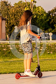 Child riding kick scooter in summer day