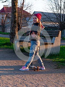 Child riding on kickscooter alone. Blonde cute girl on scooter on spring city park street background. Active lifestyle