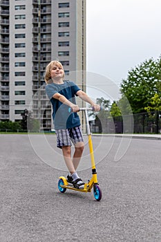 Child riding scooter. Boy spending time outdoor in summer