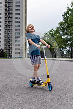 Child riding scooter. Boy spending time outdoor in summer