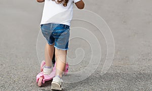 Child riding scooter. Happy little kid girl playing pink kick board on road in park outdoors on summer day, Active children games