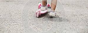 Child riding scooter. Happy little kid girl playing pink kick board on road in park outdoors on summer day, Active children games