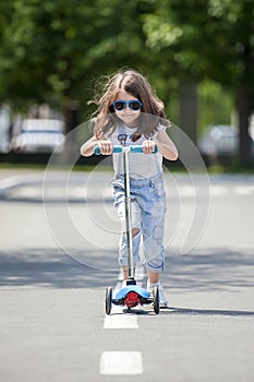 Child riding scooter. Kid on colorful kick board. Active outdoor fun for kids. Summer sports for preschool children