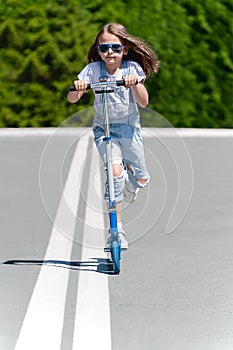 Child riding scooter. Kid on colorful kick board. Active outdoor fun for kids. Summer sports for preschool children. Little happy