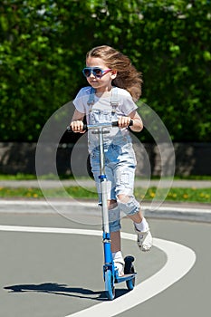 Child riding scooter. Kid on colorful kick board. Active outdoor fun for kids. Summer sports for preschool children. Little happy