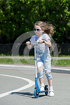 Child riding scooter. Kid on colorful kick board. Active outdoor fun for kids. Summer sports for preschool children. Little happy