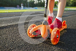 A child is riding scooter. Kid on colorful kick scooter. Active outdoor fun for kids. Summer sports for children