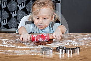 Child Rolling Gingerbread Dough on Kitchen Table with Festive Baking Tools