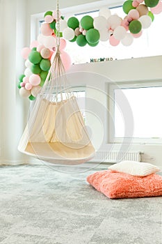 child room with hammock chair and balloons. Colorful kid room with rug, window and chair