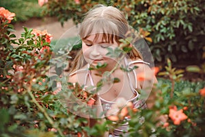 Child with rose flower in spring garden