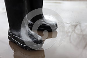 child in rubber boots in a puddle after rain