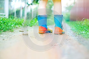 Child in rubber boots walking outdoor.