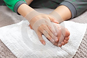 Child rubs the white powder into the foot. Foot skin hygiene.