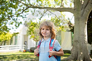 Child with rucksacks standing in the park near school. Pupils with books and backpacks outdoors. Kids education concept.