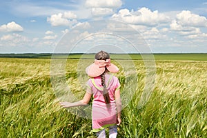 Child run through the wheat field, bright sun, beautiful summer landscape