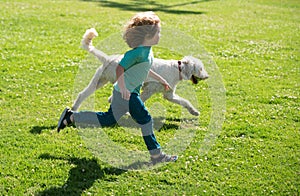 Child runnin with a dog in park. Kid with a puppy dog outdoor playing at backyard lawn.