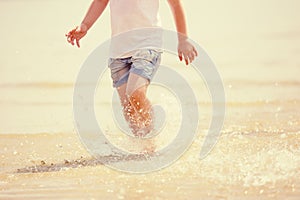 Child running beach shore splashing water