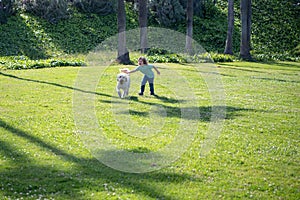 Child running with a dog. Kid with a puppy dog outdoor playing at backyard lawn. Carefree childhood.