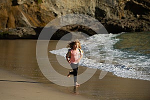 Child running through water close to shore along the sea beach. A boy runs along the sea coast. Rest of children on