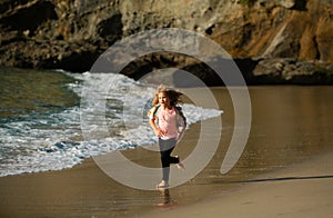 Child running through water close to shore along the sea beach. A boy runs along the sea coast. Rest of children on