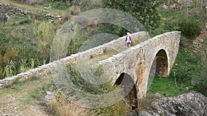 A child runs across an ancient Venetian bridge. Waving hands, playing with colorful ribbons