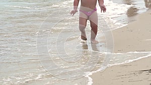 Child runs along the sea beach in the water in slow motion.