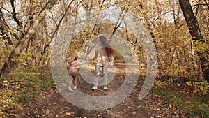 child runs around his mother and laughs in the park, happy family, cheerful child with mom plays a game, golden autumn