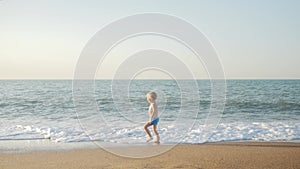 A child runs on the beach on seawater on a sunny hot summer day.