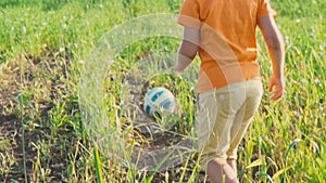 A child runs and beats the ball, young football player. 5 year old boy kicks a soccer ball with his feet on the high