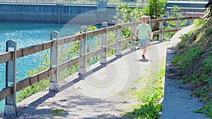 Child runs happy near a mountain lake. Slow motion effect