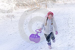 A child runs on a hill in the winter forest. Baby is playing at a ski resort. Concept of active children`s recreation. A cheerful