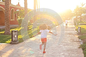 A child runs towards the sun's rays along the road