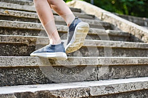 Child runs up the concrete staircase outdoor. kids feet in sneakers on steps