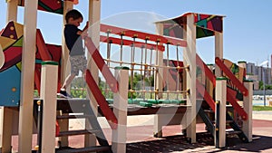 A child runs on a wooden cable bridge at a playground in an urban area