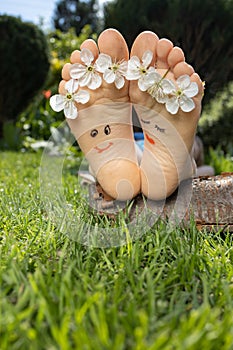 The child\'s bare feet lie on lush green grass on a sunny warm day