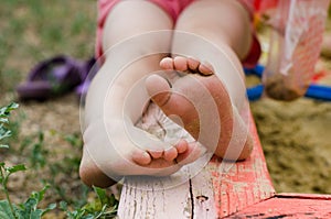 Child`s bare feet stained in sand