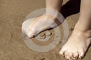 The child`s bare feet on the yellow sand