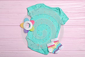 Child`s clothes and teether on pink background, flat lay